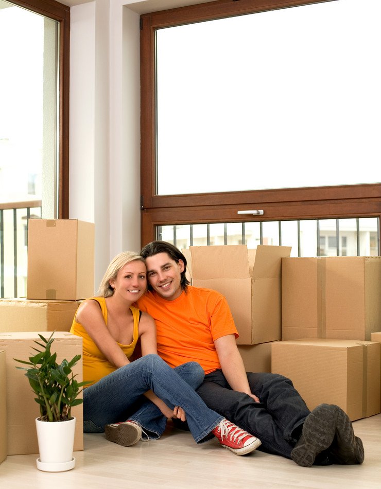Счастливая молодая семья в новой остекленной квартире, коробки с вещами