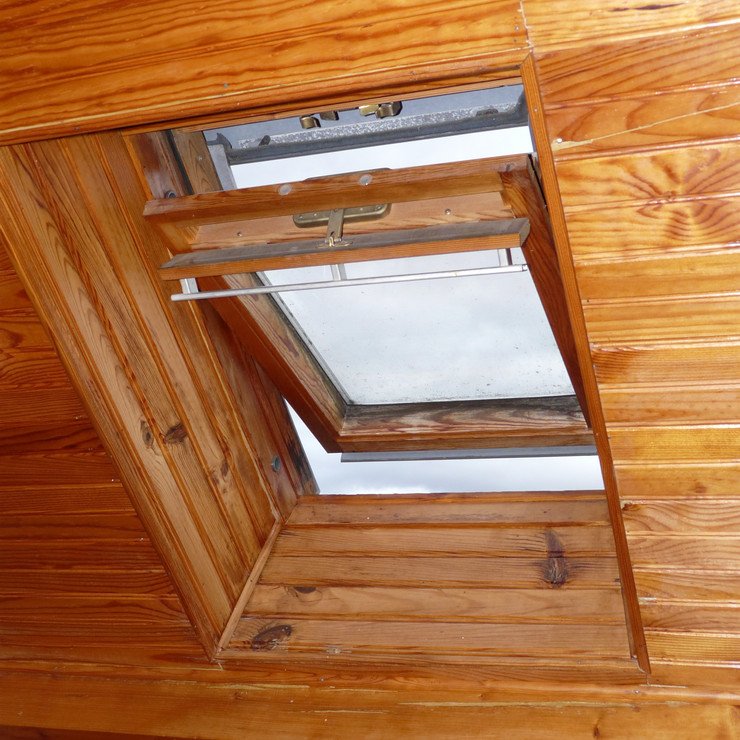 Приоткрытое окно в крыше деревянного дома