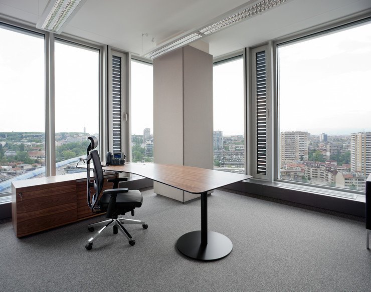 Остекленный панорамными окнами современный офис в многоэтажном здании, стол, стул