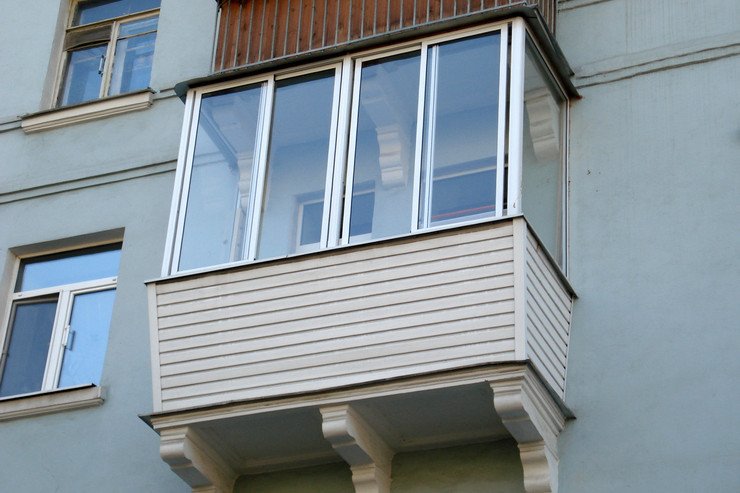 Застекленный балконный блок с сайдингом в многоэтажном доме