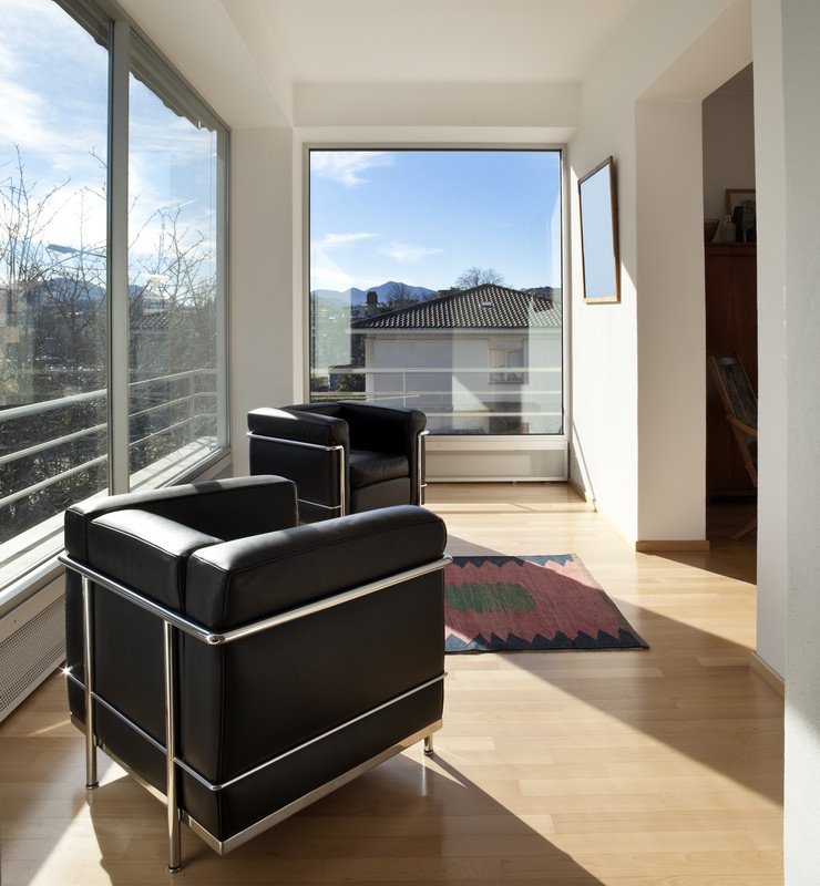Панорамное остекление лоджии, объединенной с комнатой, мягкие кресла, коврик, ламинат