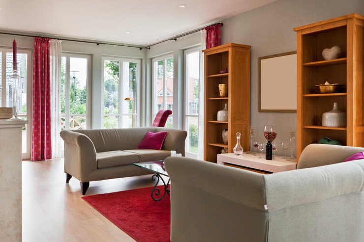 Панорамное остекление в гостиной, мягкий диван с подушкой, красные шторы