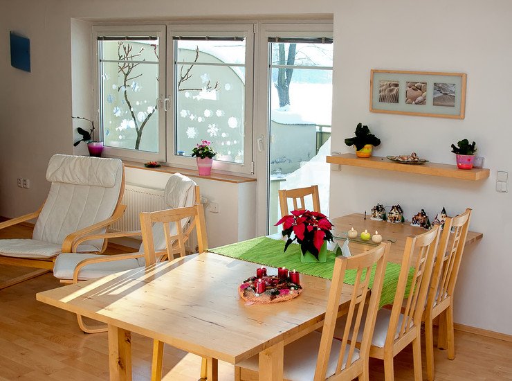 Остекленная комната, деревянный стол, стулья, кресло-качалка, цветок