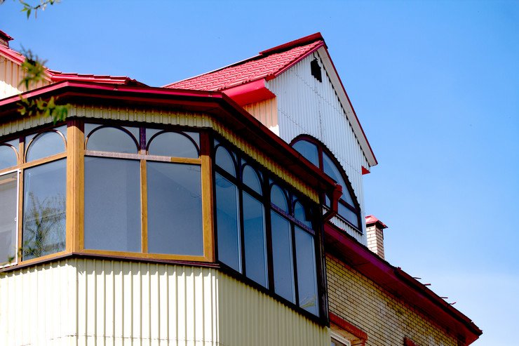 Застекленная лоджия полукругом в загородном коттедже, красная крыша