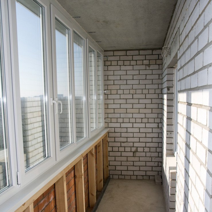 Длинный балконный блок в многоэтажном доме из белого кирпича
