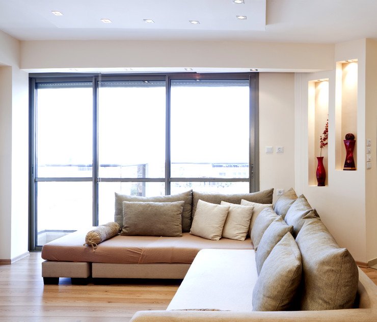 Остекленная панорамными оконными блоками гостиная, диван, подушки