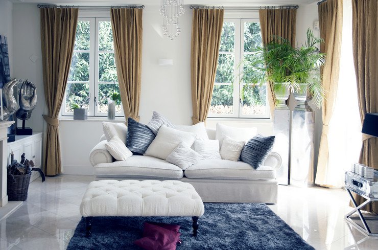 Остекленная гостиная в частном доме, мягкий диван, коврик, цветы, шторы