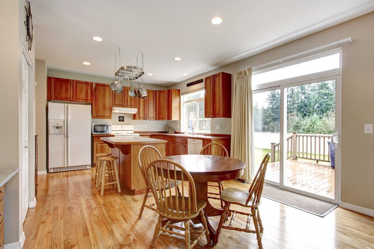 Остекленная панорамным оконными системами кухня в частном доме, деревянные стулья, стол