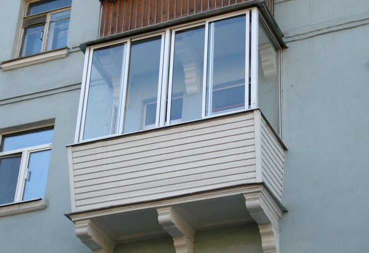 Застекленный балконный блок с сайдингом в многоэтажном доме